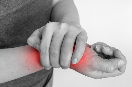 Woman with wrist pain is holding her aching hand - black and white body pain conceptの写真素材