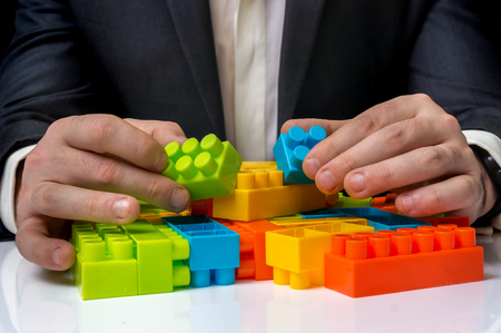 Concept of strategy and reorganization business ideas - young businessman playing with colored toy blocksの写真素材