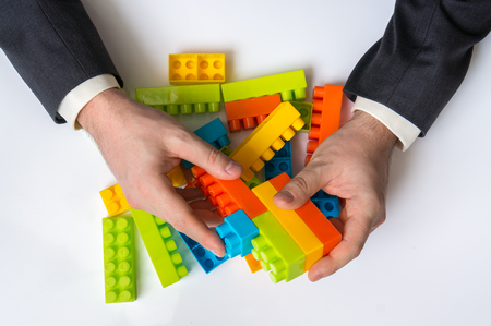Concept of strategy and reorganization business ideas - young businessman playing with colored toy blocksの写真素材