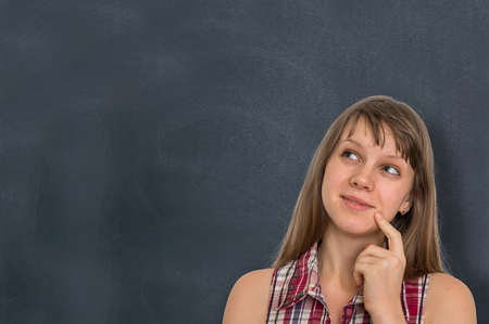 Thoughtful woman with empty blackboard - education conceptの写真素材