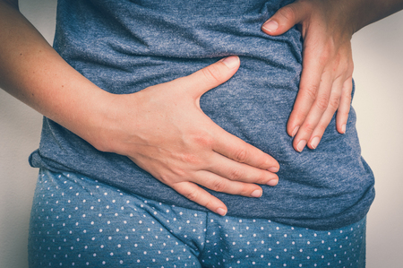 Woman with stomach pain is holding her aching belly - body pain concept - retro styleの写真素材