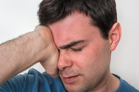 Man with eyes pain is holding his aching eye - body pain conceptの写真素材