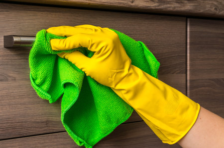 Hand in glove with green rag is cleaning stainless steel handles - housework and housekeeping...