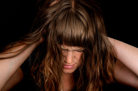 Depressed woman with hands in her hair isolated on black backgroundの写真素材