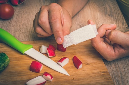 Woman is applying  plaster on her finger - injury in kitchen - retro styleの写真素材