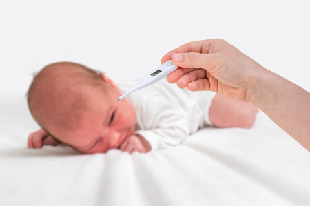 Measuring temperature to a newborn baby with digital thermometer - cold and flu conceptの写真素材