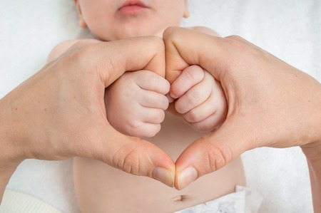 Newborn baby holding mother hands in heart shape - family love conceptの写真素材