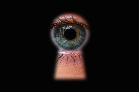 Human eye behind door looking through a keyhole - voyeurism conceptの写真素材
