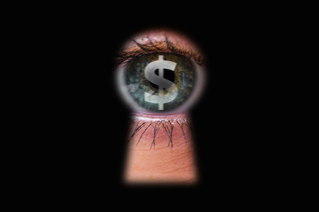 Human eye with dollar symbol looking through a keyholeの写真素材