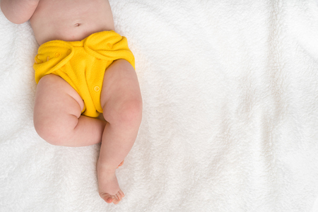 Newborn baby in diaper lying on white blanket - top viewの写真素材