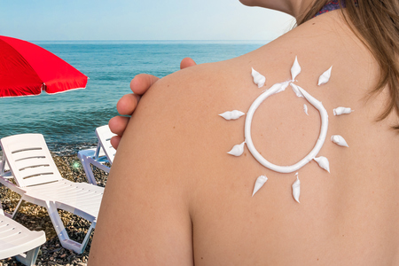 Woman with suntan lotion on her shoulder in sun shape - sunbathing conceptの写真素材