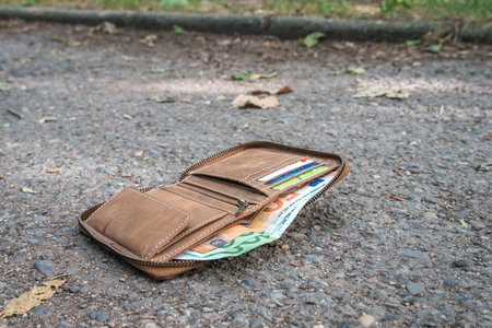 Lost leather wallet with money on the ground on street