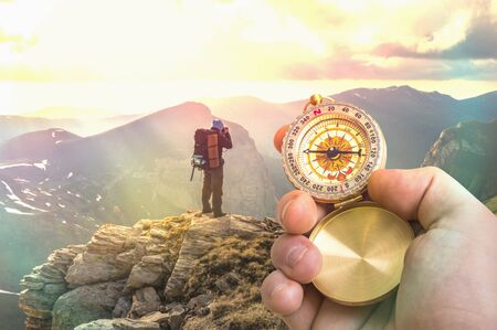 Traveler man with compass seeking a right way in the mountains - navigation conceptの写真素材