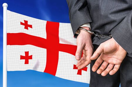 Prisons and corruption in Georgia. Businessman with handcuffs on national flag background.の写真素材