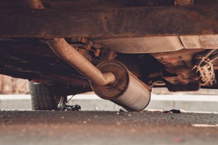 Car exhaust, muffler fallen down on the ground - view of rusty chassis of a carの写真素材