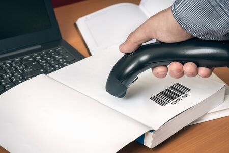 Man with scanner scans barcode in a bookの写真素材