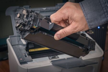 Man is replacing black cartridge in a laser printerの写真素材