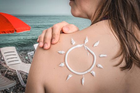 Woman with suntan lotion on her shoulder in sun shape - sunbathing concept - retro styleの写真素材