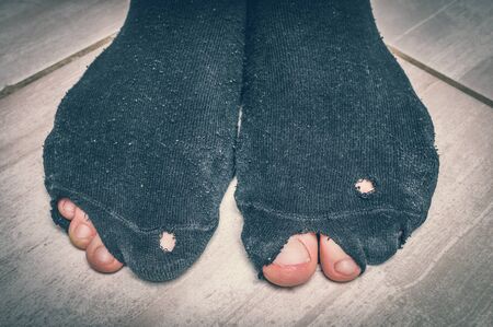 Worn socks with a holes and a fingers sticking out of them - economic crisis concept - retro styleの写真素材