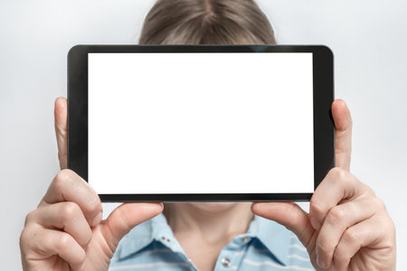 Black tablet with blank white touch screen in hands of womanの写真素材