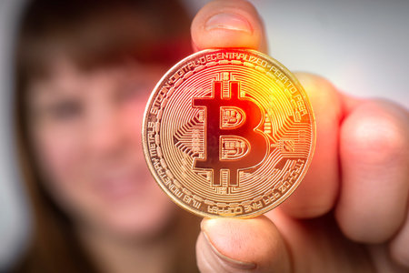 Woman with golden bitcoin in her hand - cryptocurrency concept