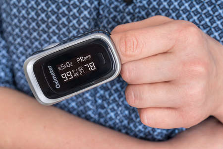 Woman with oximeter is measuring oxygen saturation and heart pulse rate from her fingerの写真素材