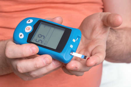 Man with diabetes is checking blood sugar level with glucose meterの写真素材