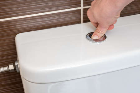 Hand of woman flush toilet after using - hygiene conceptの写真素材