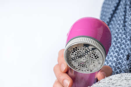 Woman is removing lint with fabric shaver or fuzz remover - clothes care conceptの写真素材