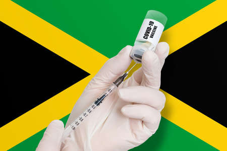 Vaccination in Jamaica. Vaccine to protect against Covid-19 on background of national flag.の写真素材