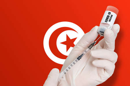 Vaccination in Tunisia. Vaccine to protect against Covid-19 on background of national flag.の写真素材