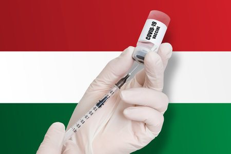 Vaccination in Hungary. Vaccine to protect against Covid-19 on background of national flag.の写真素材