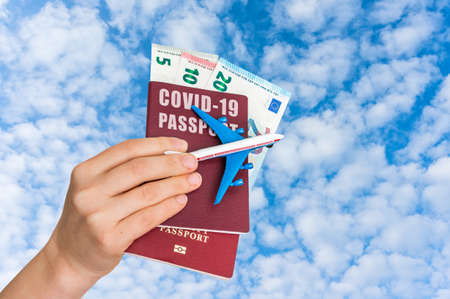 Covid-19 passport for free travel through the world with airplane model in hands of womanの写真素材