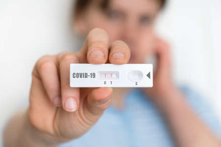 Rapid test on COVID-19 in hands of woman with positive resultの写真素材