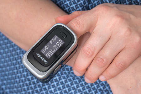 Woman with oximeter is measuring oxygen saturation and heart pulse rate from her fingerの写真素材
