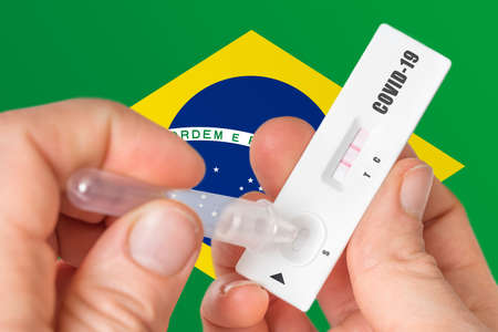 Positive rapid test on COVID-19 in Brazil on background of national flagの写真素材
