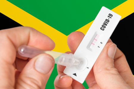 Positive rapid test on COVID-19 in Jamaica on background of national flagの写真素材
