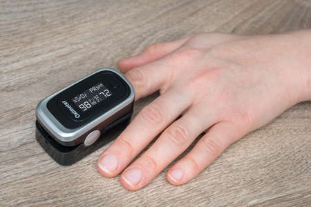 Woman with oximeter is measuring oxygen saturation and heart pulse rate from her fingerの写真素材