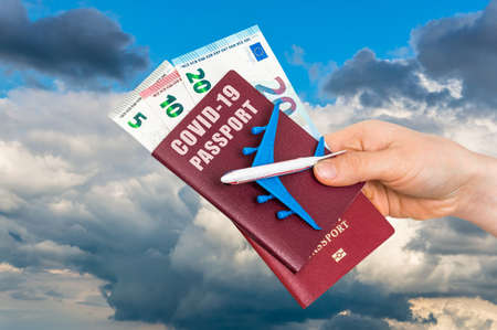 Covid-19 passport for free travel through the world with airplane model in hands of womanの写真素材