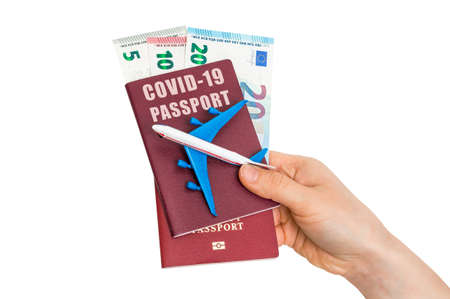 Covid-19 passport for free travel through the world with airplane model in hands of womanの写真素材