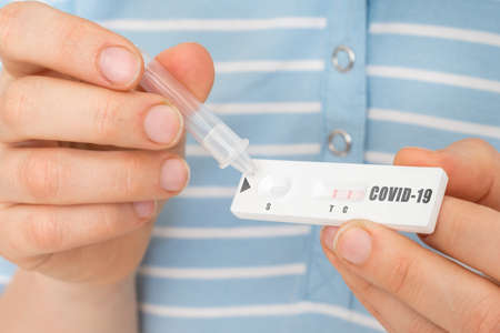 Rapid test on COVID-19 in hands of woman with positive resultの写真素材