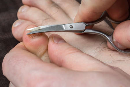 Man cutting nails on his foot - pedicure conceptの写真素材
