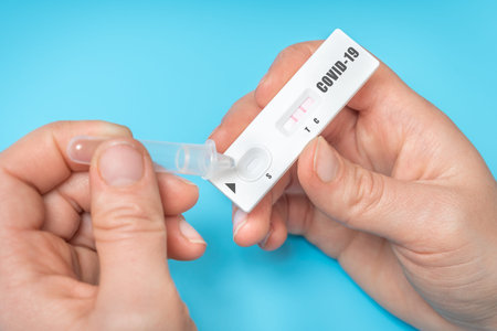 Rapid test on COVID-19 in hands of woman with positive result - isolated on blue background
