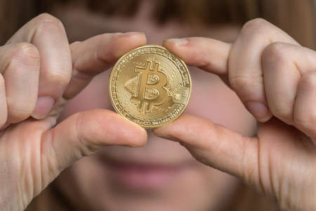 Woman with golden bitcoin in her hand - cryptocurrency conceptの写真素材