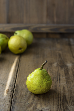 one fresh ripe organic yellow pear on rustic wooden brown table with defocused pears on background. Selective focus. Vertical with copy space. For design about agricilture, fruit and healthy foodの写真素材