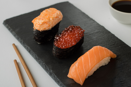 Japanese sushi on flat black plate made from natural stone, chopsticks and gravy boat with soy sauceの写真素材