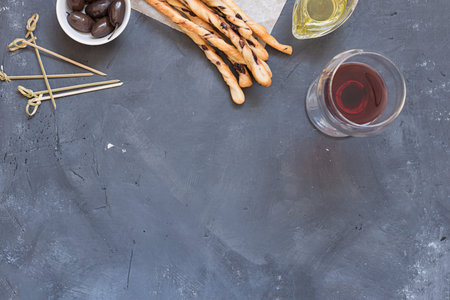 Many orange home made grissini with pieces of black olives on pieve of baking paper, skewers on,...