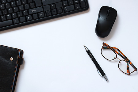 Flat lay photo of Office table with black keyboard, notebook, mouse, Pen, eyeglasses on white background. Desktop office concept. flat lay. life styleの写真素材