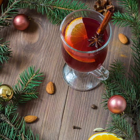 Mulled red wine with spices in glass with Christmas decoration. brown wooden background. Close up.の写真素材