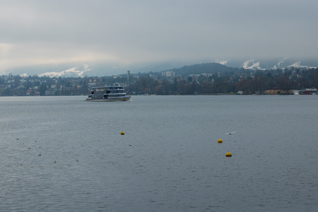 Stemboat on the Lake of Zurich with the background of foggy mountains with snowy tops. Wintertime. Scenery. Blue and grey colours. Sightseeing. Travelling.の写真素材